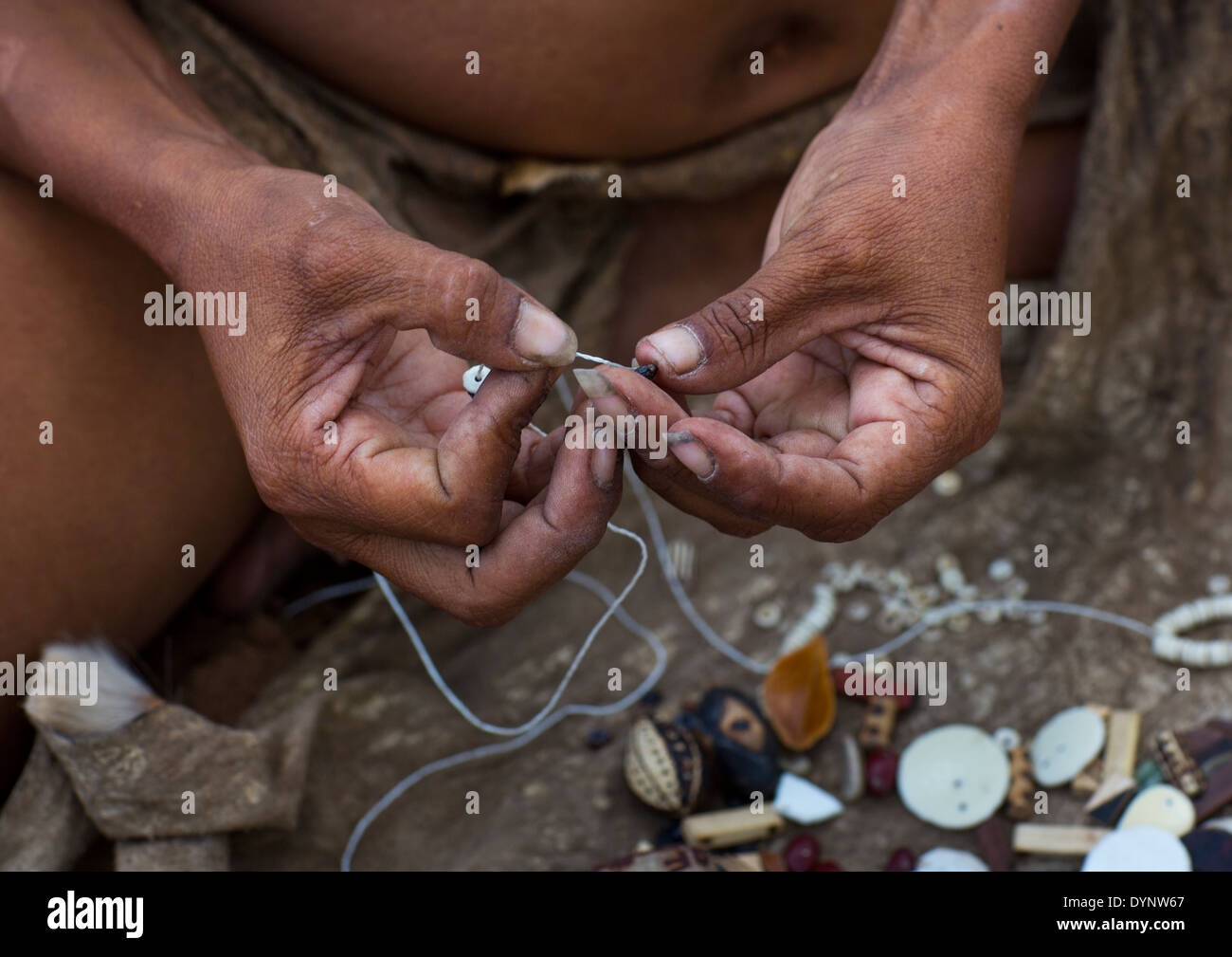 Donna boscimane facendo collane con uovo di struzzo Shell, Tsumkwe, Namibia Foto Stock