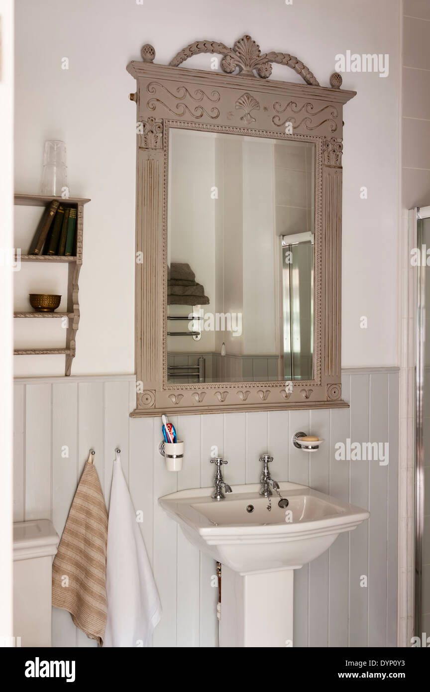 Il francese in legno in stile cornice a specchio con dettagli scolpiti e mazzo di fiori al di sopra di una vasca di lavaggio Foto Stock
