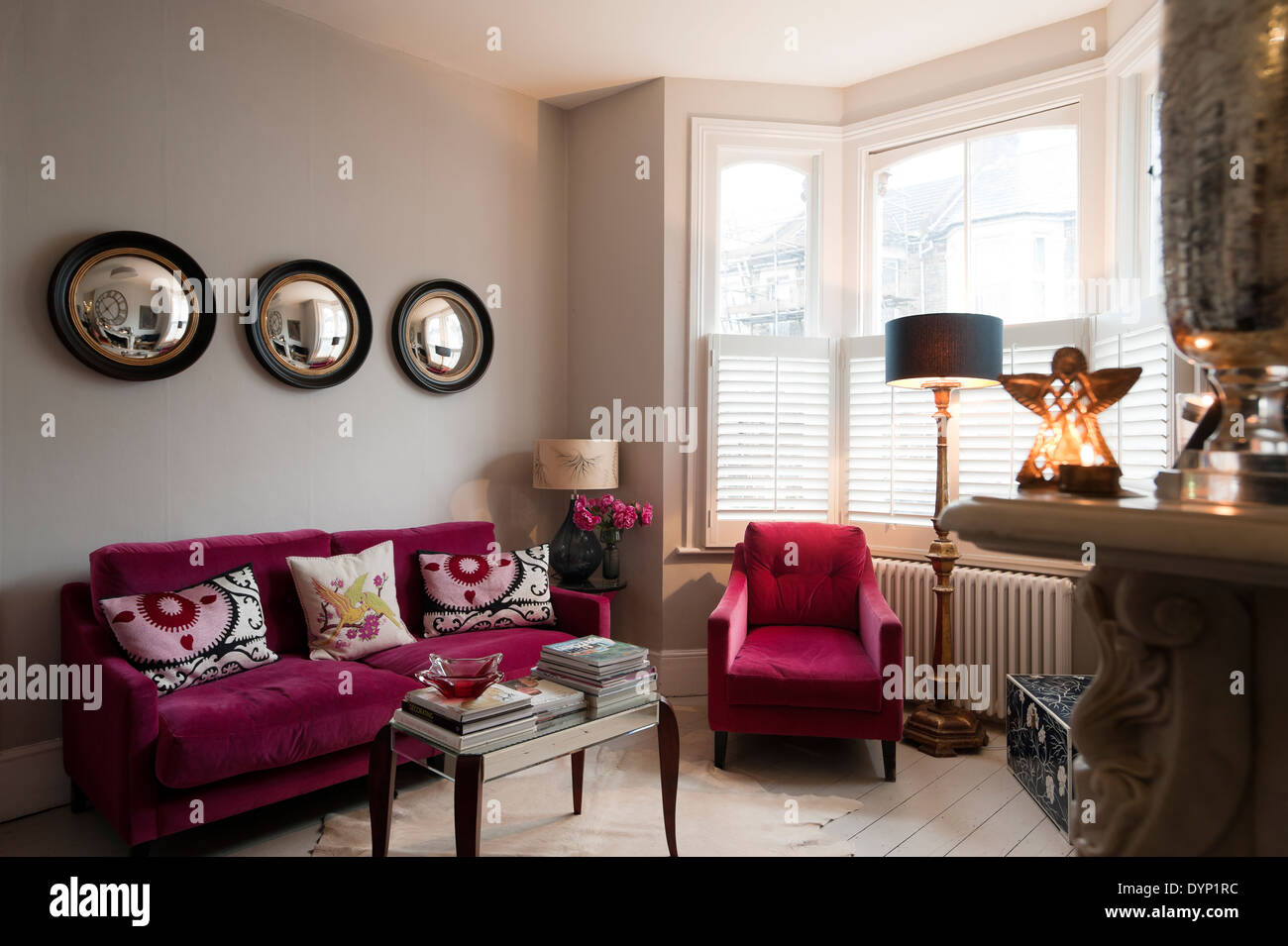 Lampone velluto colorato arredamento in salotto con Graham e oblò verde specchi da parete Foto Stock