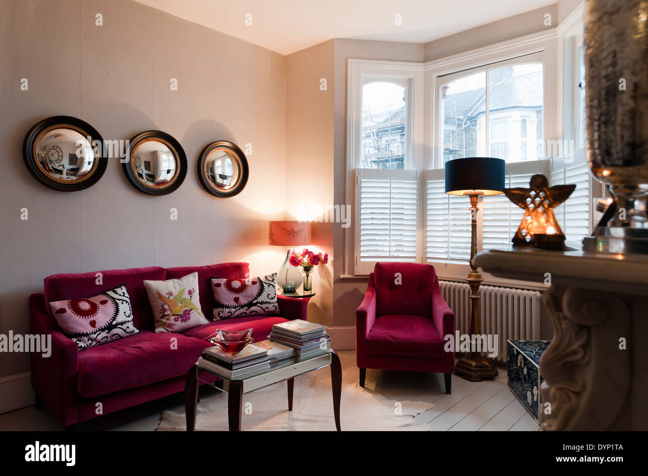 Lampone velluto colorato arredamento in salotto con Graham e oblò verde specchi da parete Foto Stock