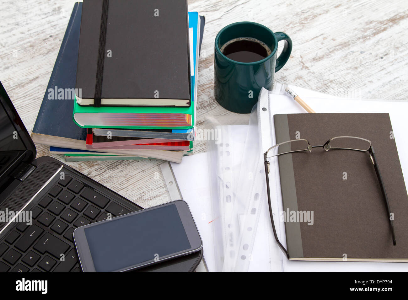 Lavorare con il portatile, una pila di libri e bere un caffè Foto Stock