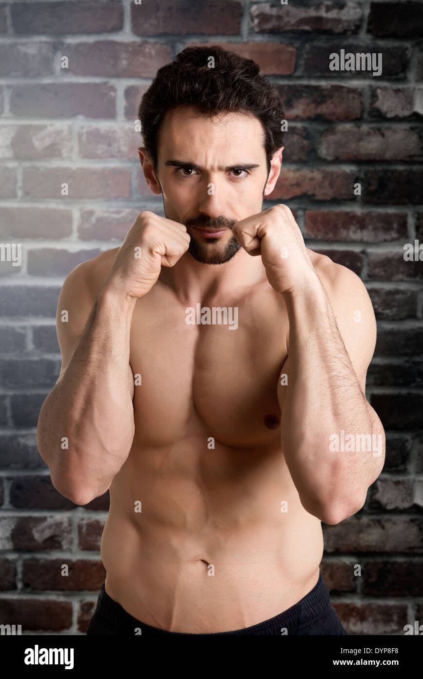 Boxer maschio pronto a combattere di fronte a un muro di mattoni Foto Stock