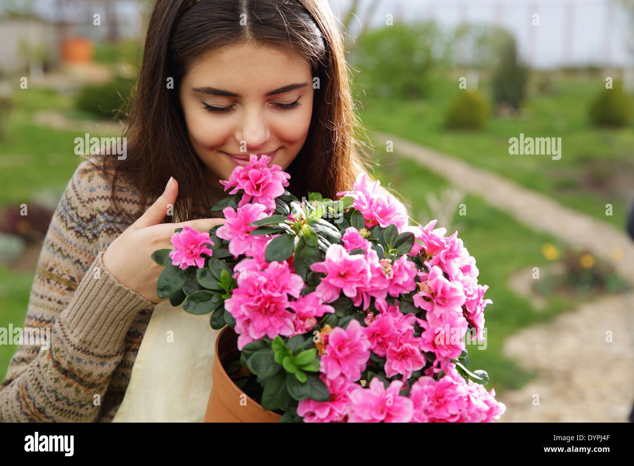 Giovane donna profumati fiori di colore rosa in giardino Foto Stock