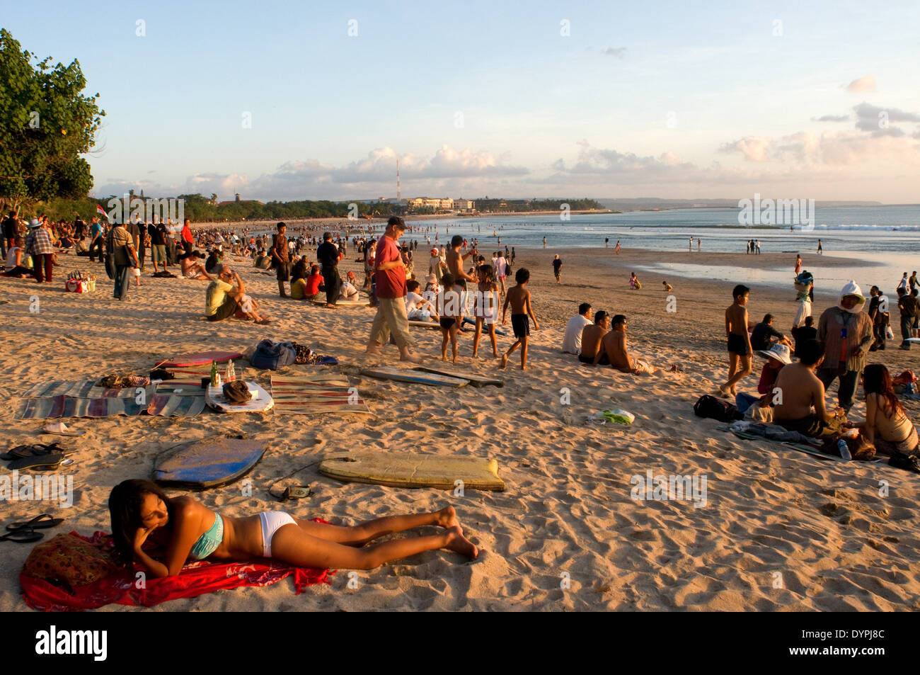 Al tramonto tutti si raduna per guardare il tramonto con una birra sulla spiaggia di Kuta. Surfisti sulla spiaggia di Kuta. Lezioni di surf. Foto Stock