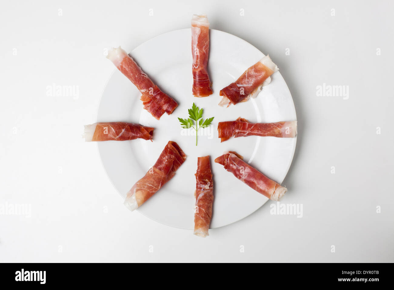 Rotoli di prosciutto spagnolo su una piastra bianca Foto Stock