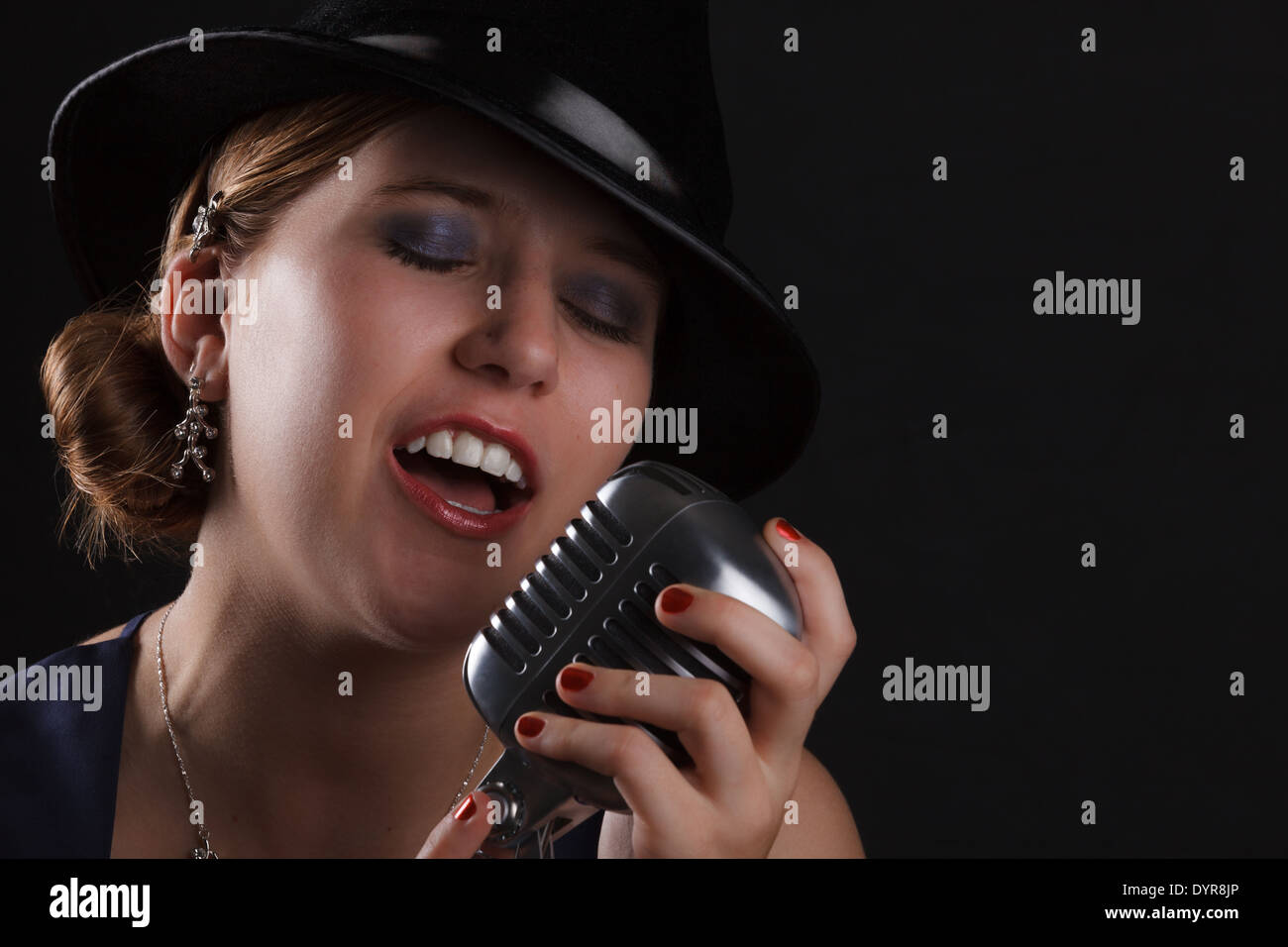 Bellissimo canto jazz donna con fedora e stile retrò microfono Foto Stock
