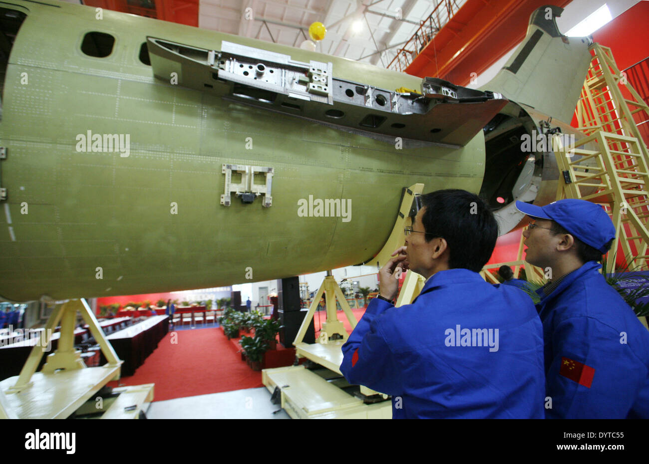 2 lavoratori cinesi guarda un ARJ 21 aeromobili commerciali in corrispondenza di una linea di assemblaggio durante una cerimonia di gruppo a Shanghai Foto Stock
