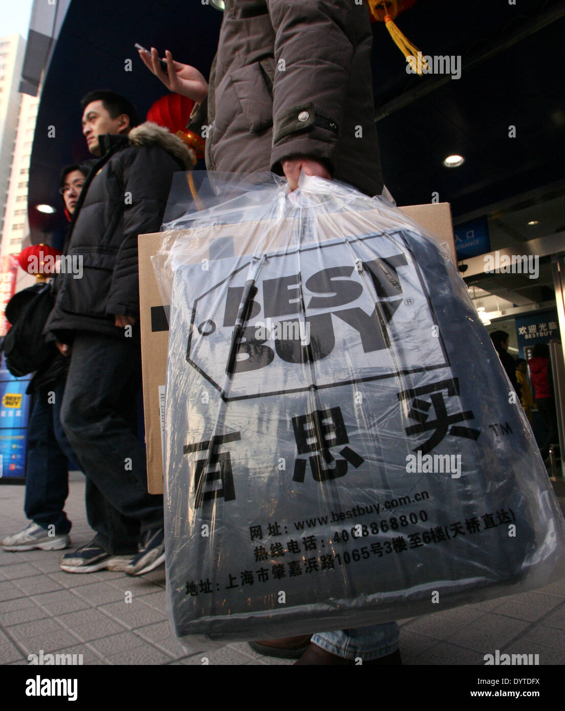 Un cliente porta un Best Buy shopping bags passeggiate fuori un negozio Best Buy in Shanghai Foto Stock