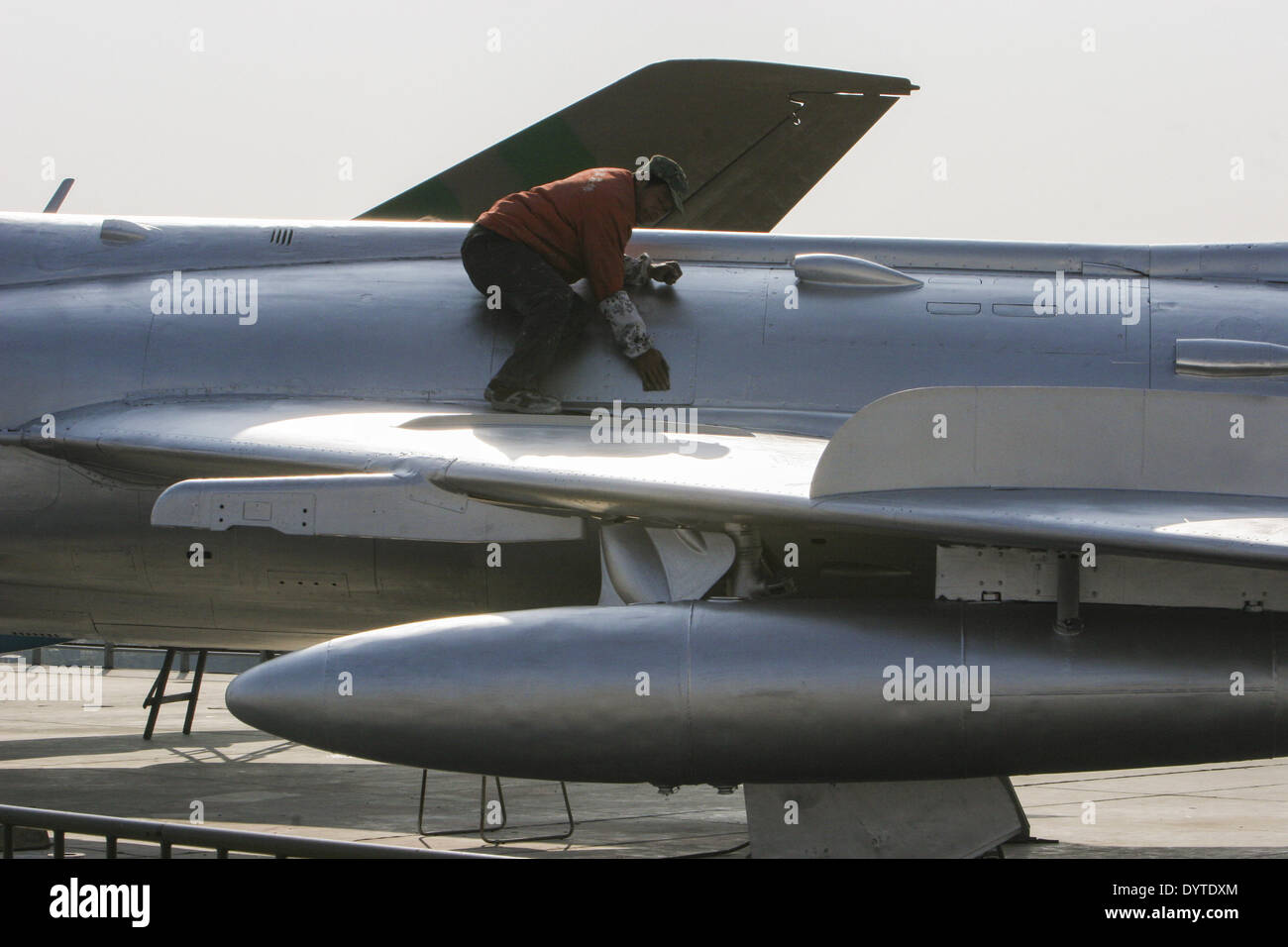 Un lavoratore dipingere un modello di jet da combattimento che si erge sul ponte di una piena dimensione modello di cemento di un US Navy classe Nimitz aeromobile Foto Stock