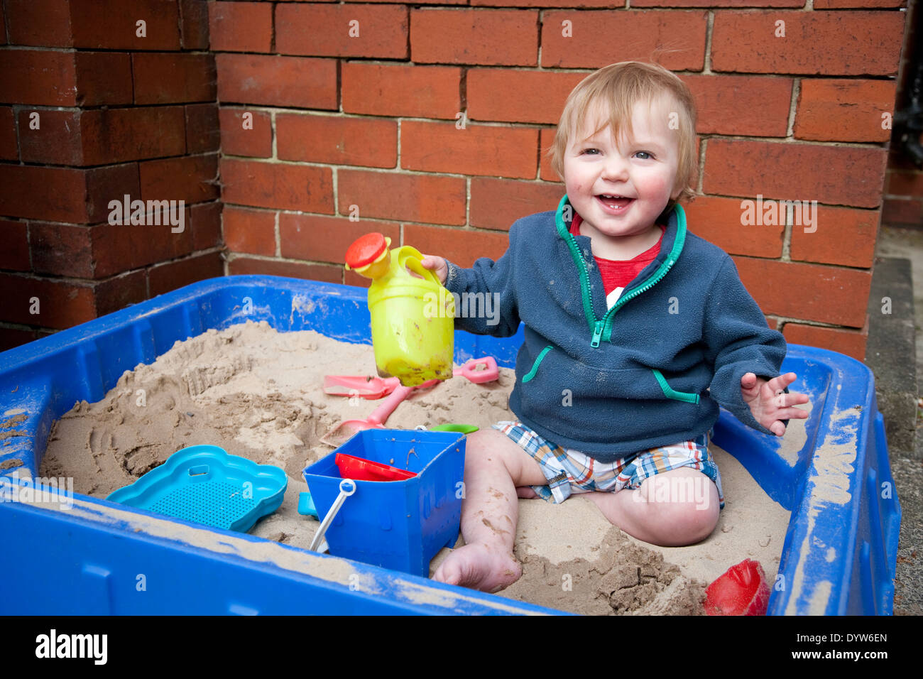Giovane ragazzo giocando nella buca di sabbia Foto Stock