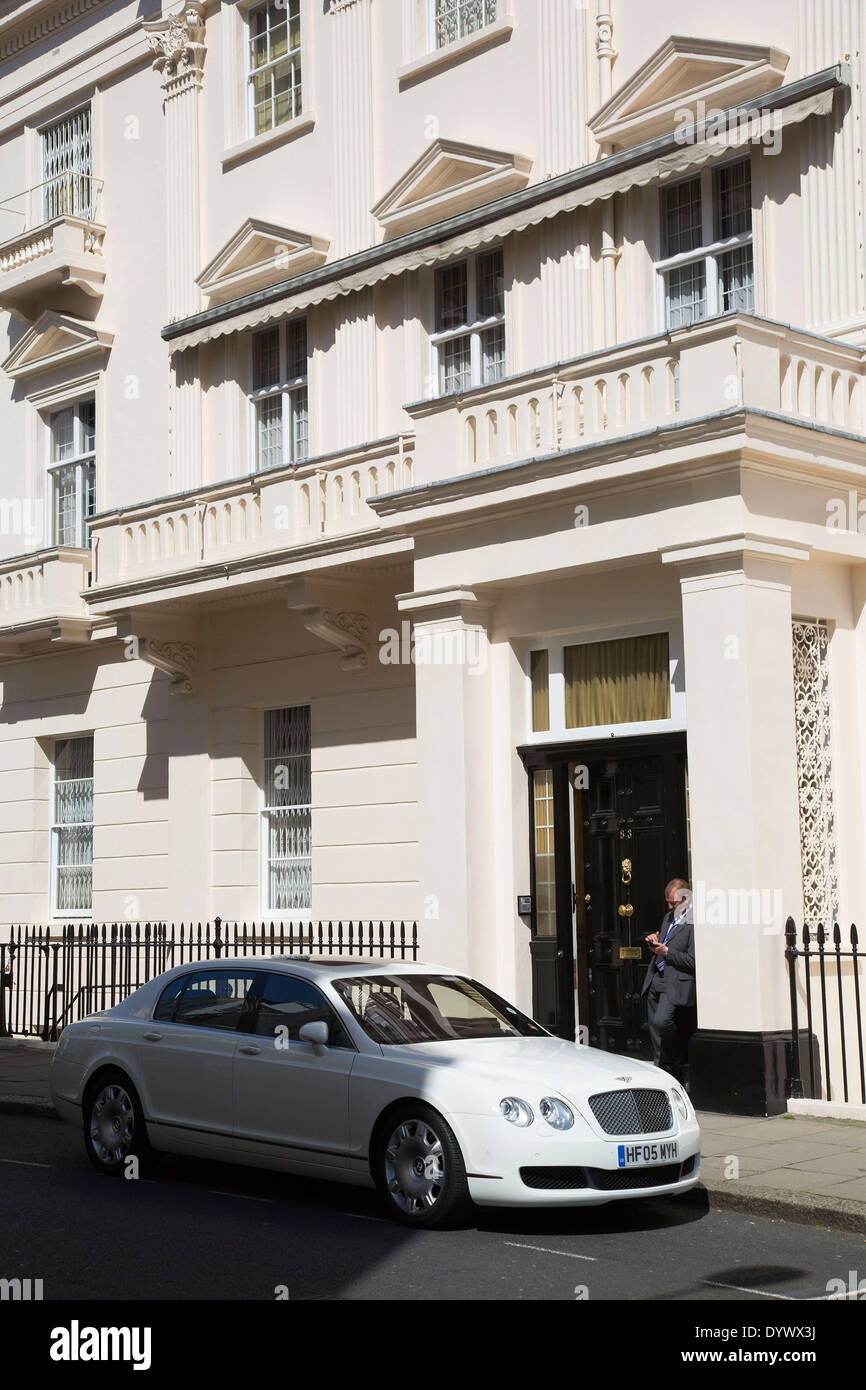 In attesa del driver esterno guardando dopo una Bentley auto in un grand indirizzo nel quartiere di Belgravia. Ricchezza e benessere nella zona ovest di Londra, Regno Unito. Foto Stock