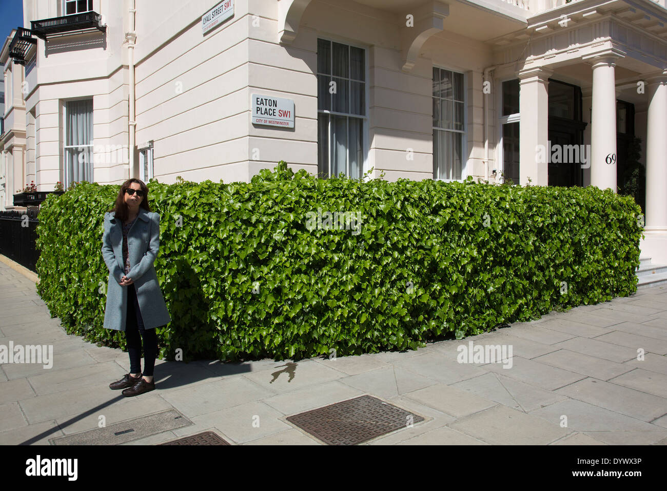 La donna in attesa su un angolo a Eaton Place. Ricchezza e benessere nella zona ovest di Londra, Regno Unito. Foto Stock