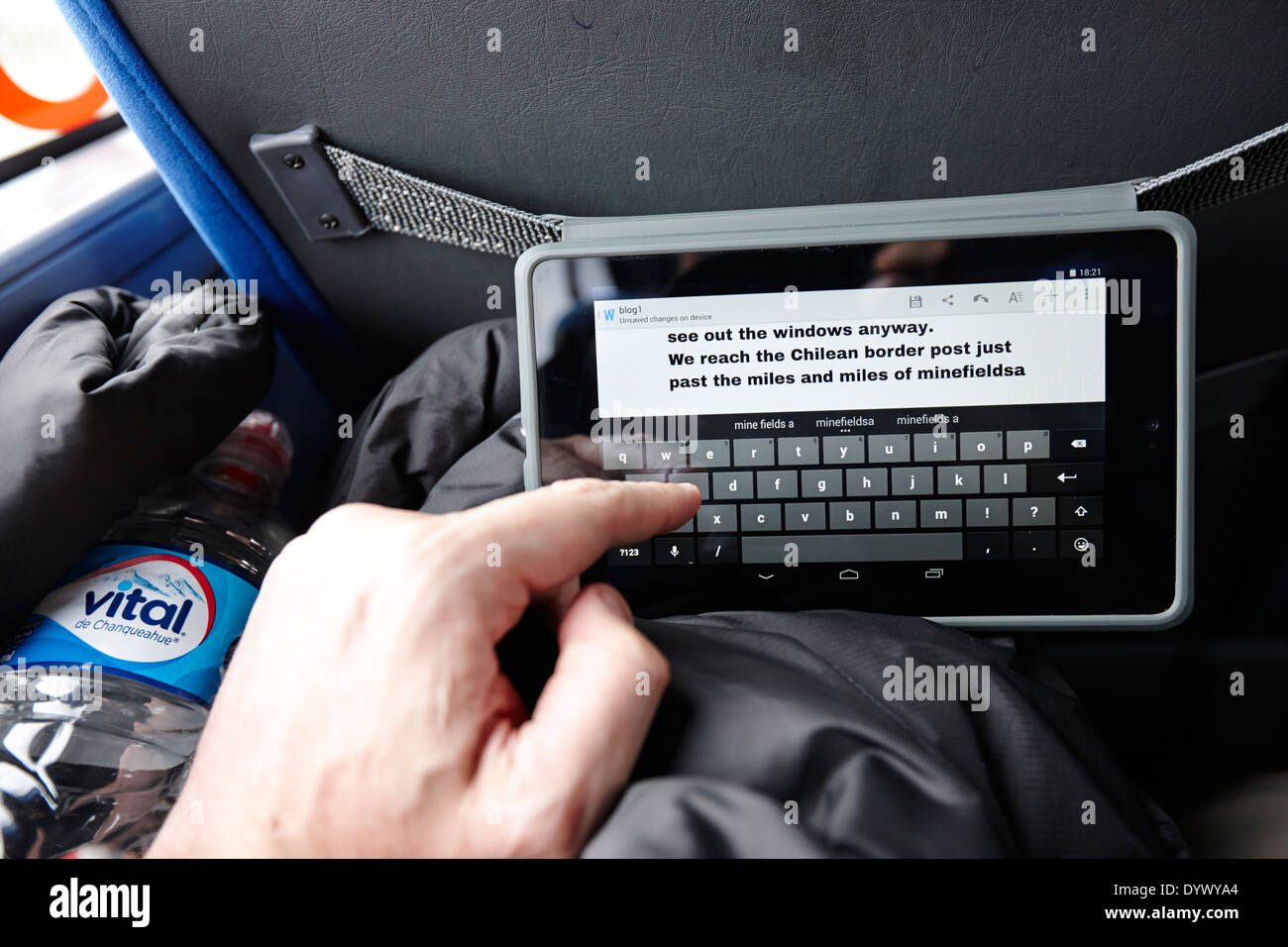 Uomo che utilizza computer tablet per scrivere blog mentre viaggia su un bus in Sud America Foto Stock