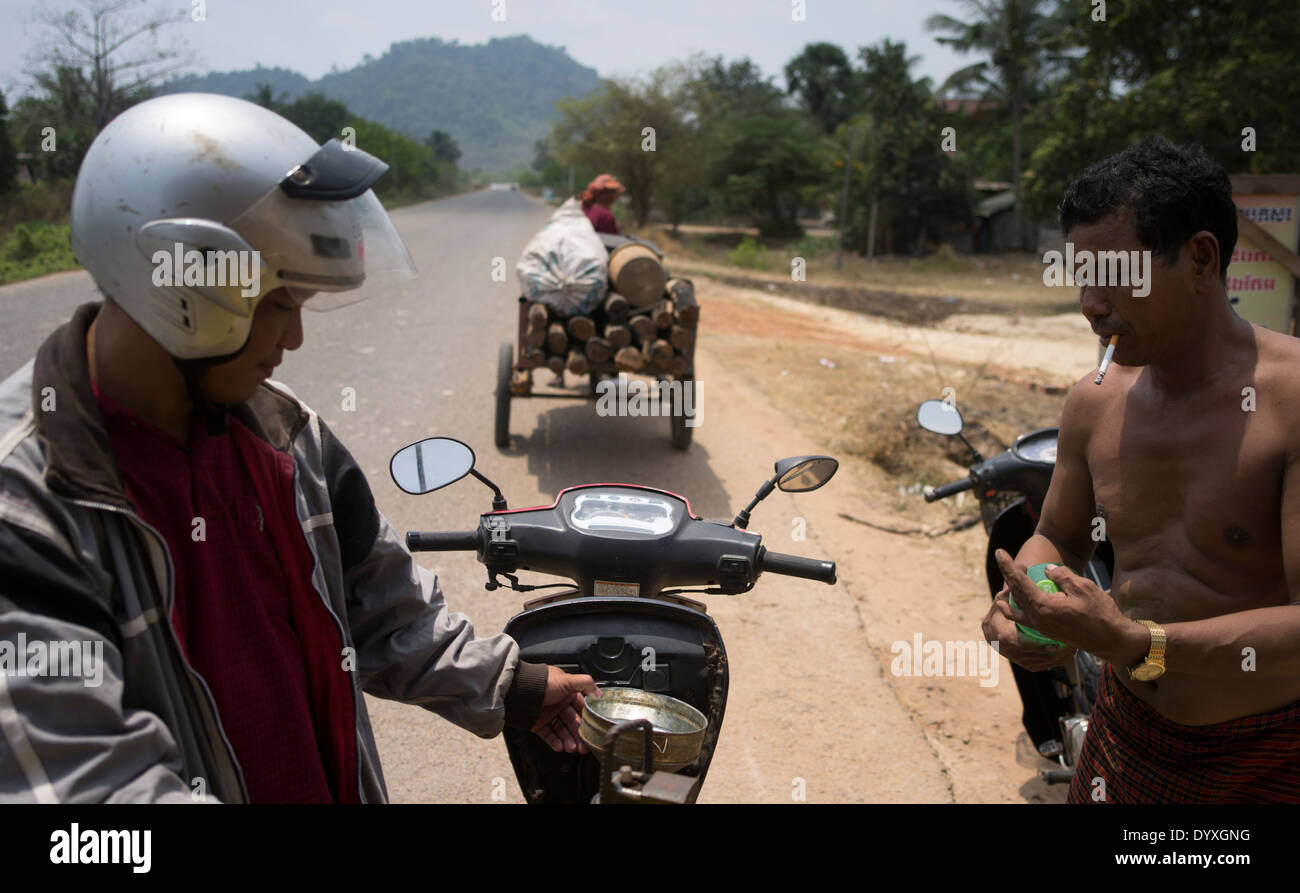 Uomo di fumare mentre versando benzina a gas stradale stazione ( benzina ) Siem Reap, Cambogia Foto Stock
