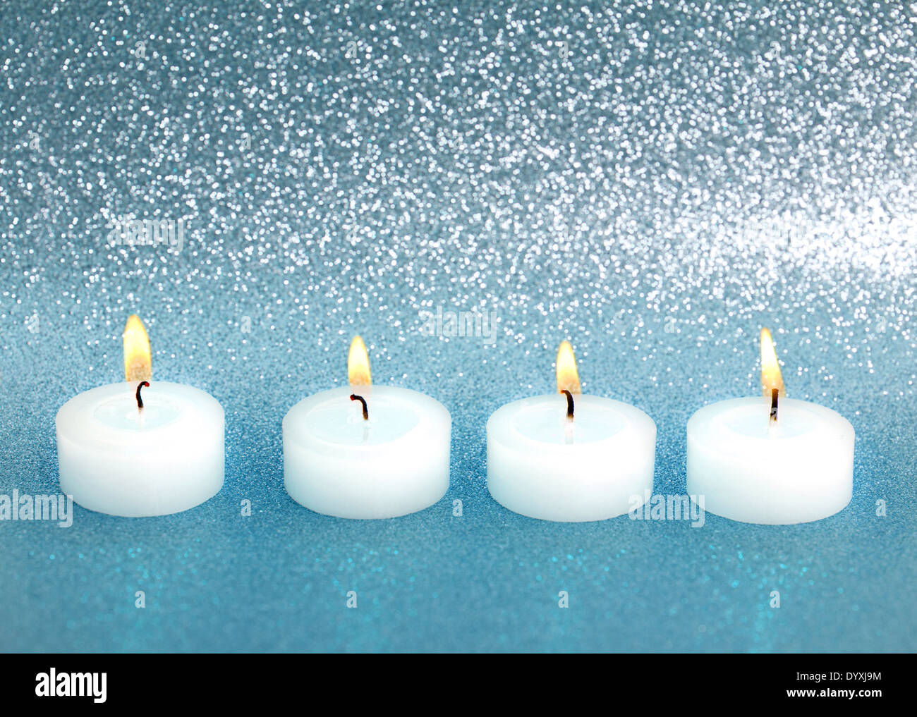 Quattro candele di masterizzazione su Blu argento sfondo lucido Foto Stock