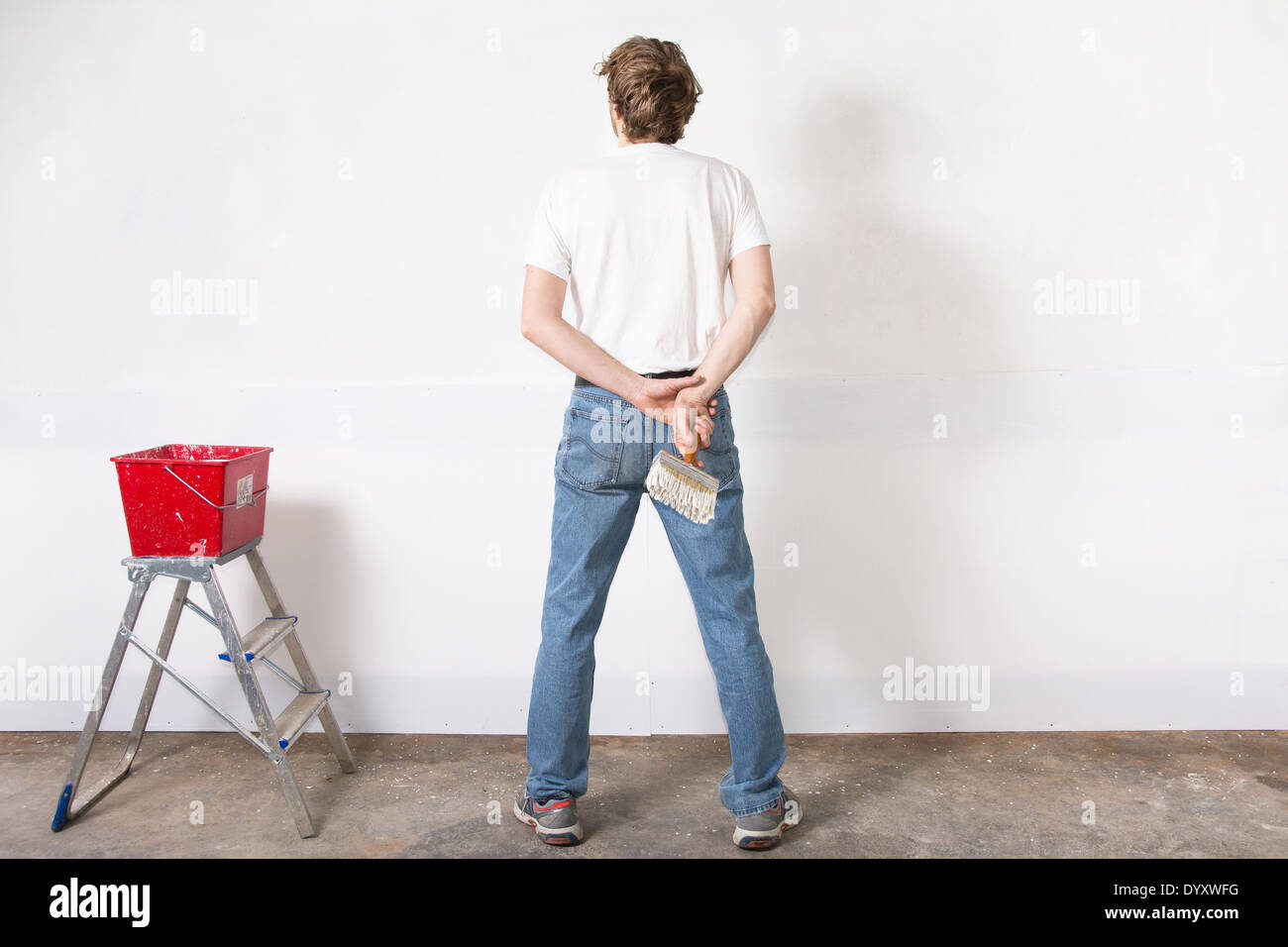 L'uomo pittura un muro bianco con spazzola di vernice Foto Stock