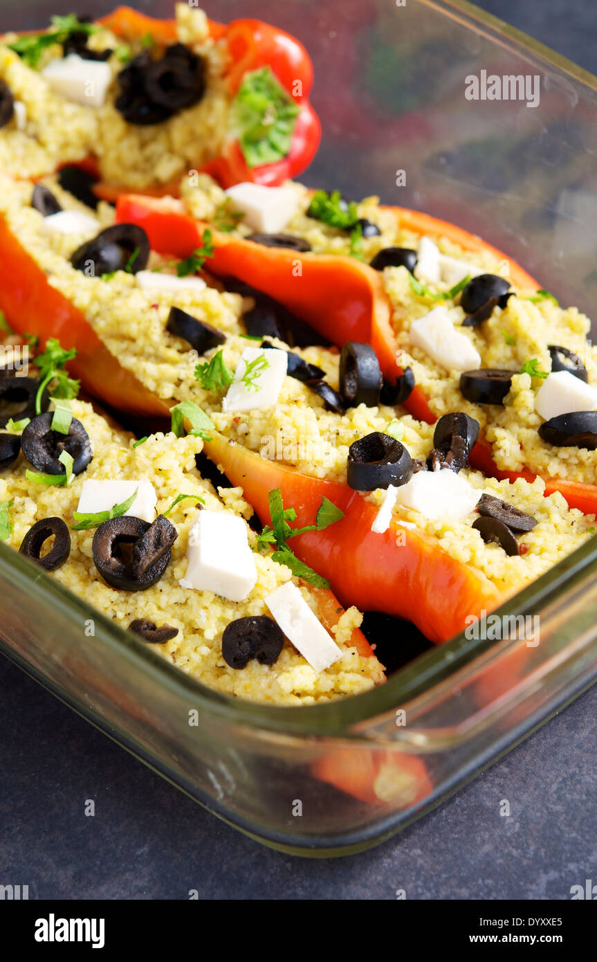Il couscous riempite i peperoni con olive e formaggio vegano in un forno a prova di piatto di cottura prima della cottura per circa venti minuti. Foto Stock