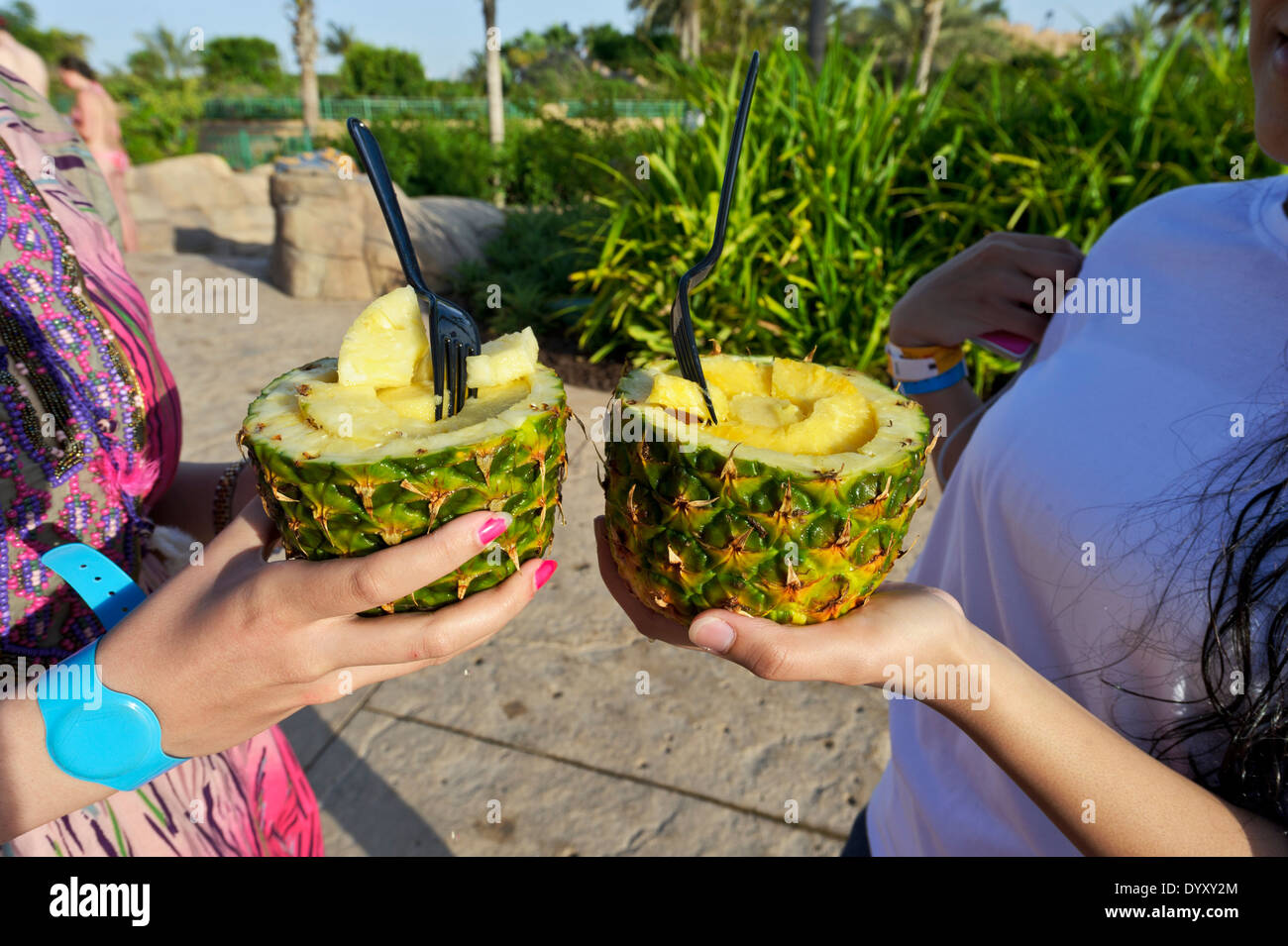 Due adolescenti holding alcuni tagliano ananassi acquistati presso il Wild Wadi Waterpark, Dubai, Emirati Arabi Uniti, Emirati arabi uniti. Foto Stock