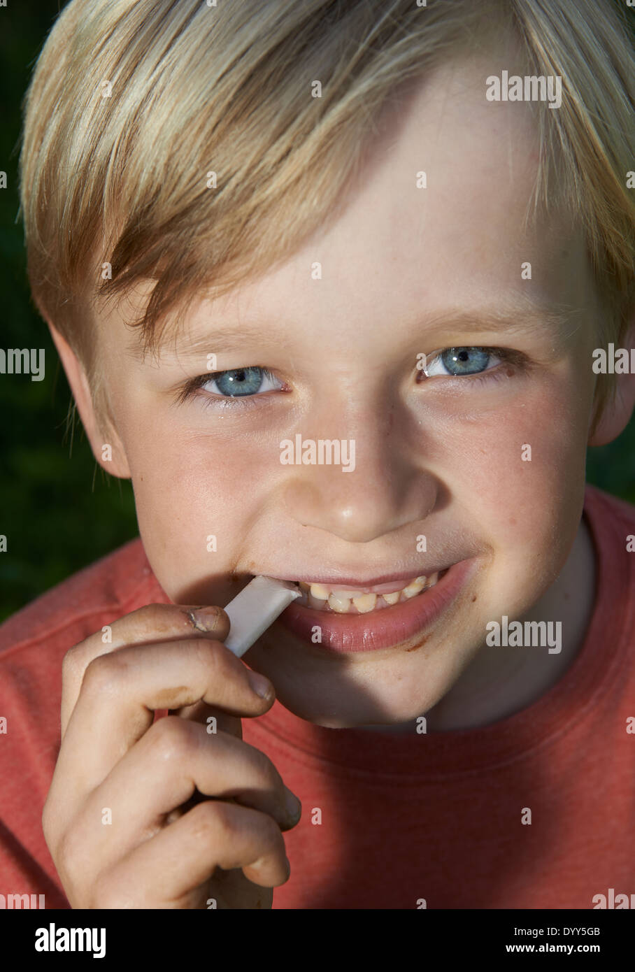 Ritratto di bambino ragazzo biondo Stretching Bubble Gum in bocca Foto Stock