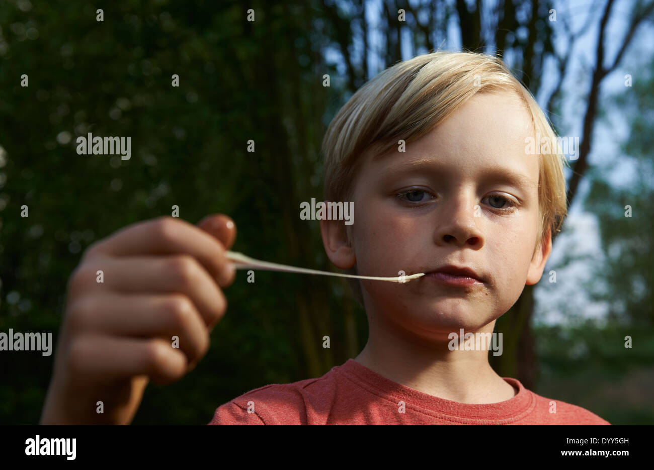 Ritratto di bambino ragazzo biondo Stretching Bubble Gum in bocca Foto Stock