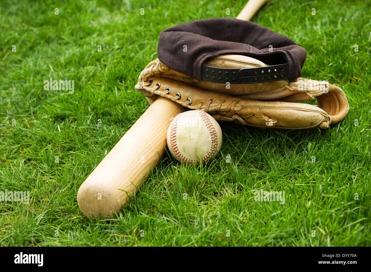 Foto orizzontale di vecchi baseball bat, cappuccio e guanto sul campo in erba naturale Foto Stock