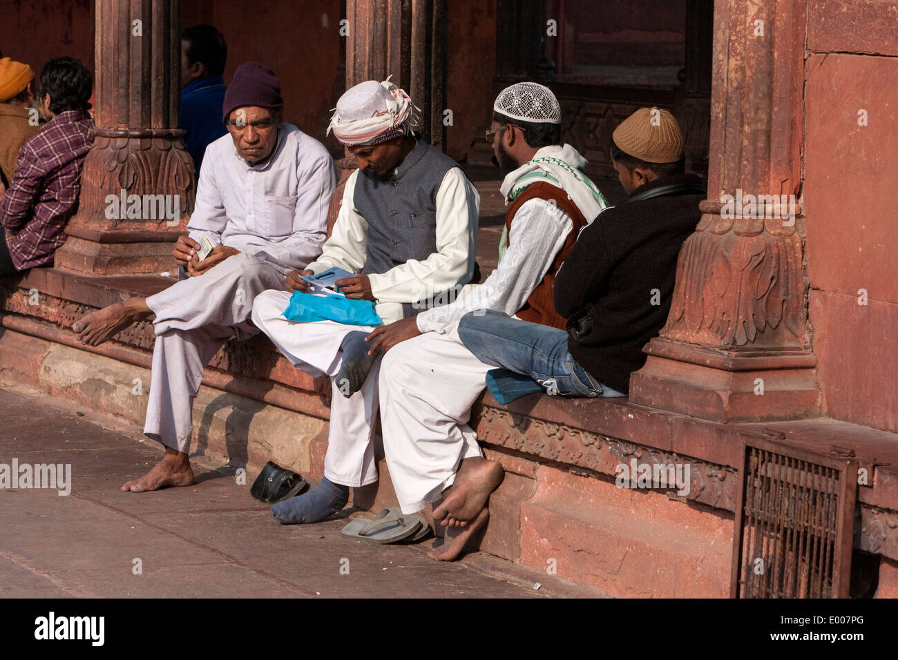 New Delhi, India. Uomini musulmani in attesa per il momento di preghiera presso la Jama Masjid (Moschea del Venerdì). Nota variando Hat stili. Foto Stock