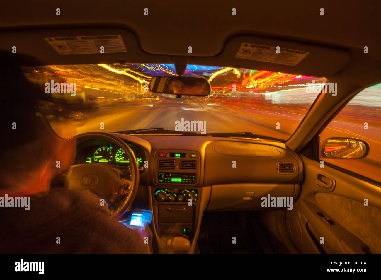 Uomo alla guida di auto durante la notte con le luci della città-Victoria, British Columbia, Canada. Foto Stock