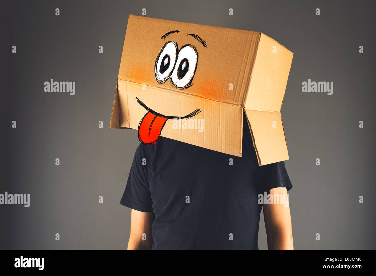 Felice uomo sorridente con scatola di cartone sulla sua testa che mostra la linguetta Foto Stock