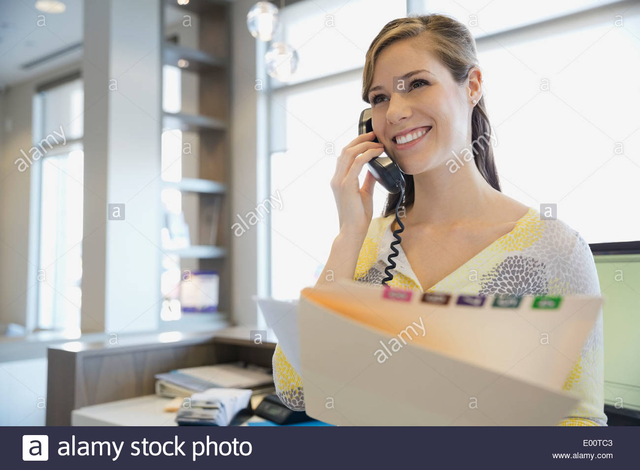 Receptionist con record medico parlando al telefono Foto Stock