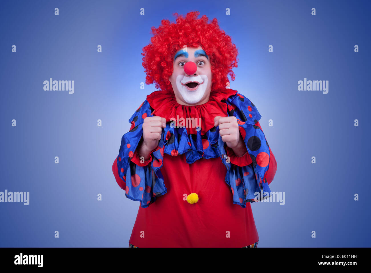 Happy clown in costume rosso su sfondo blu. Studio di illuminazione professionale Foto Stock