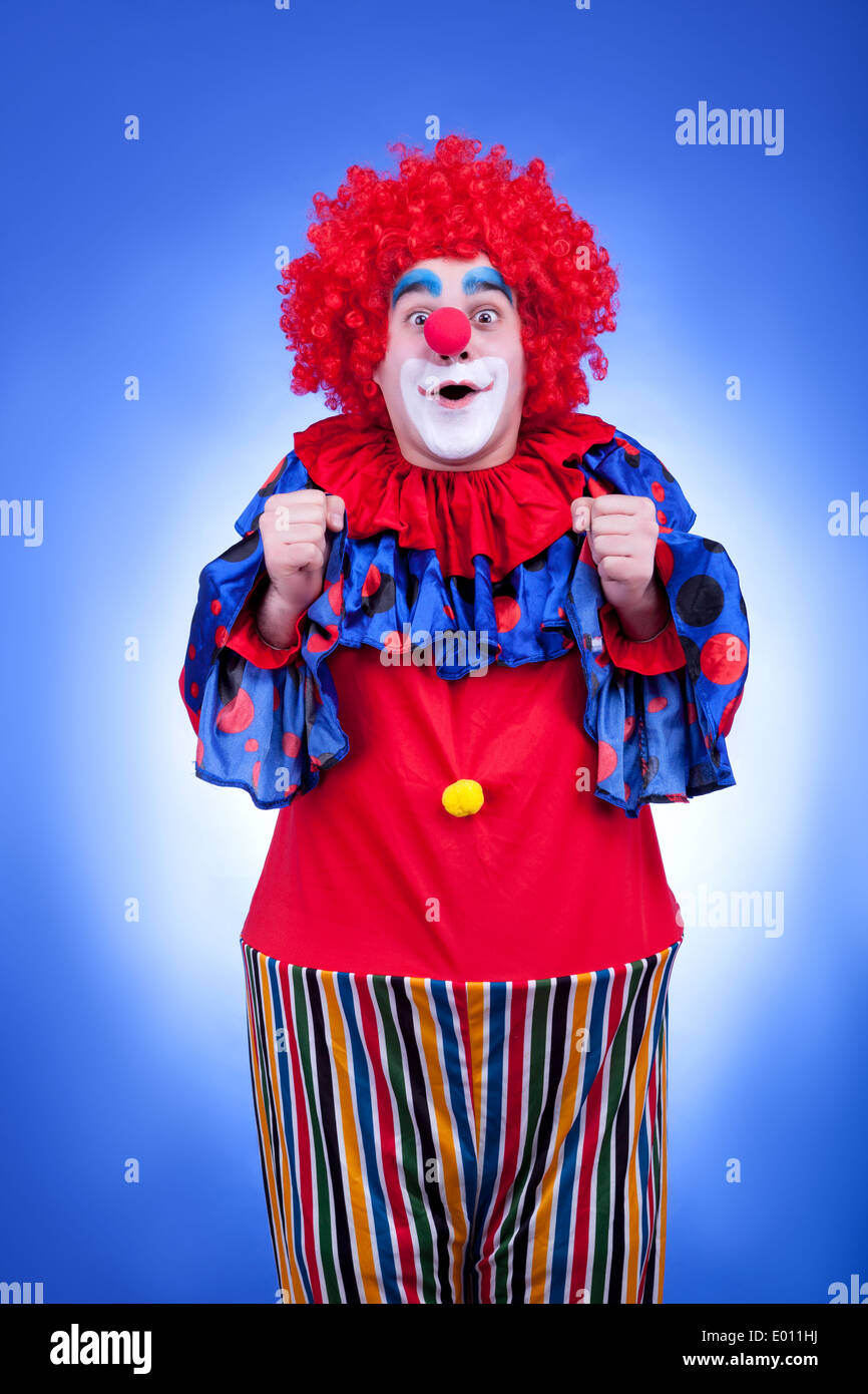 Happy clown in costume rosso su sfondo blu. Studio di illuminazione professionale Foto Stock