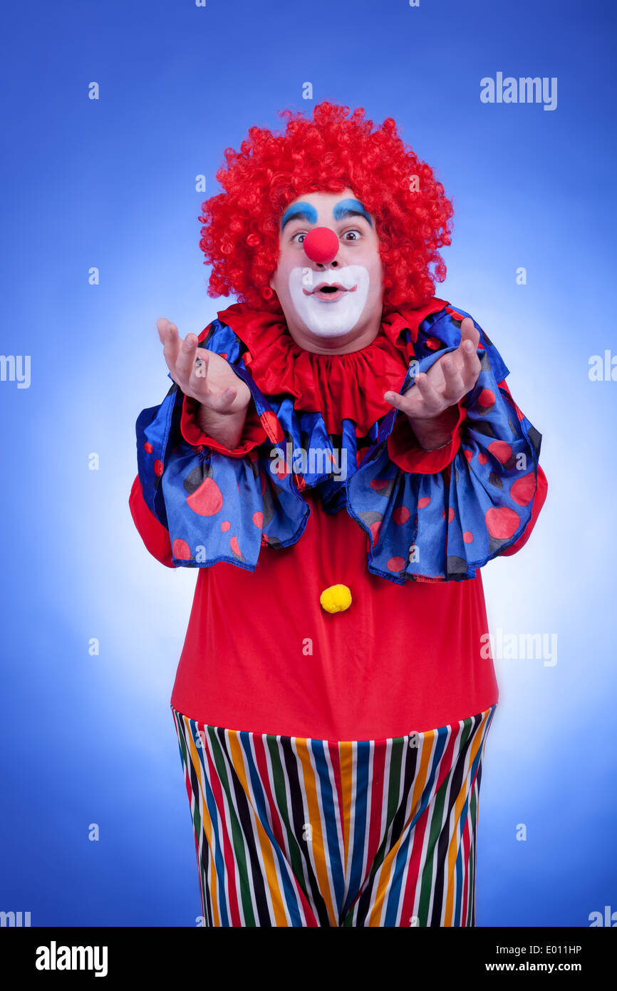Clown di uomini in costume rosso su sfondo blu. Studio di illuminazione professionale Foto Stock