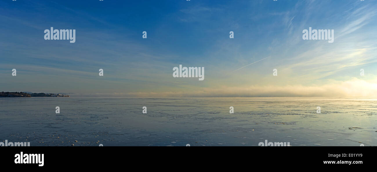 Un Penobscot Frozen River in Stockton molle Maine con distante un banco di nebbia e striato sky. Foto Stock