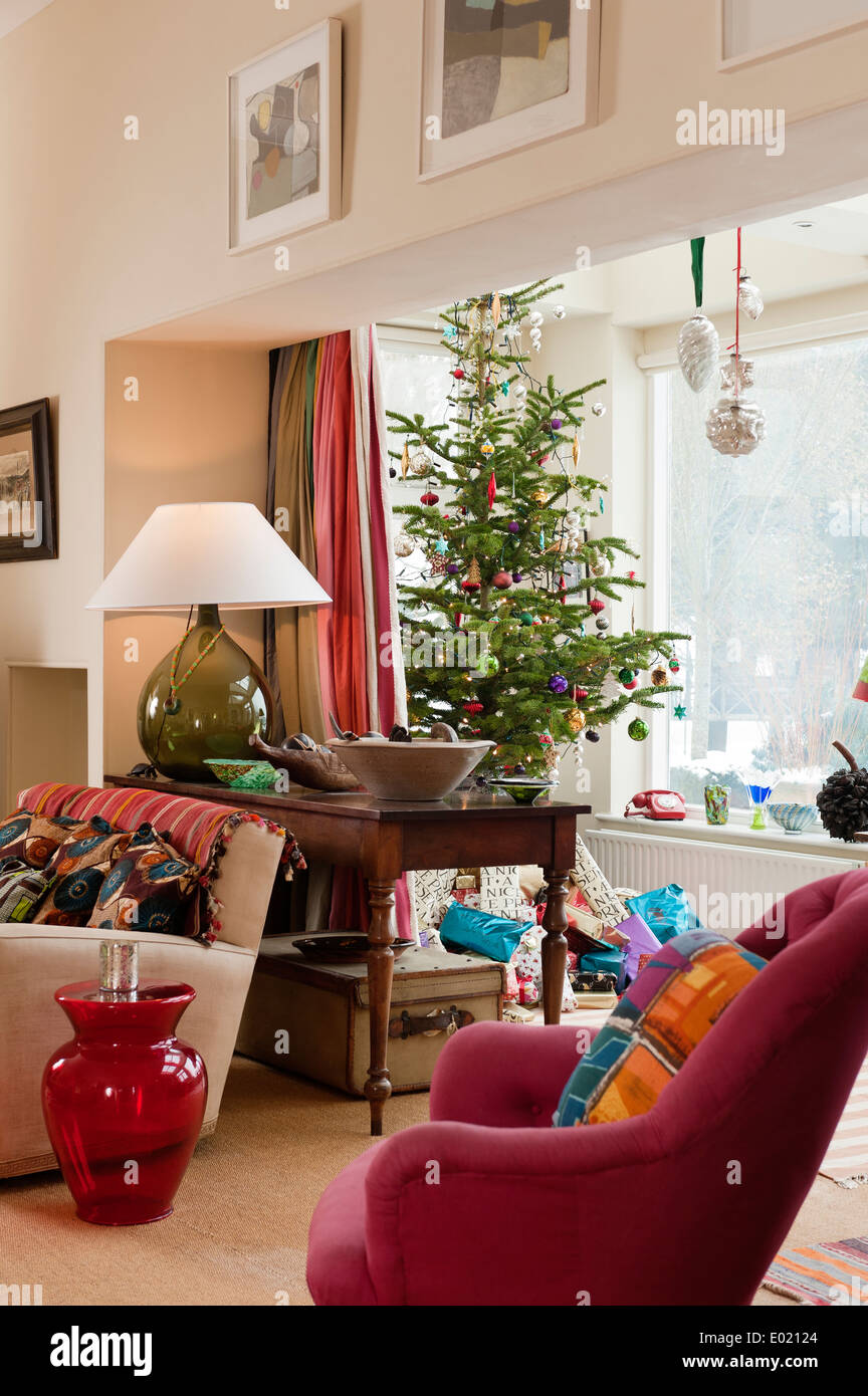 Piccola poltrona rosa in salotto con decorazioni di Natale, Philippe Starck sgabello e un TMO bottiglia di vetro spia Foto Stock