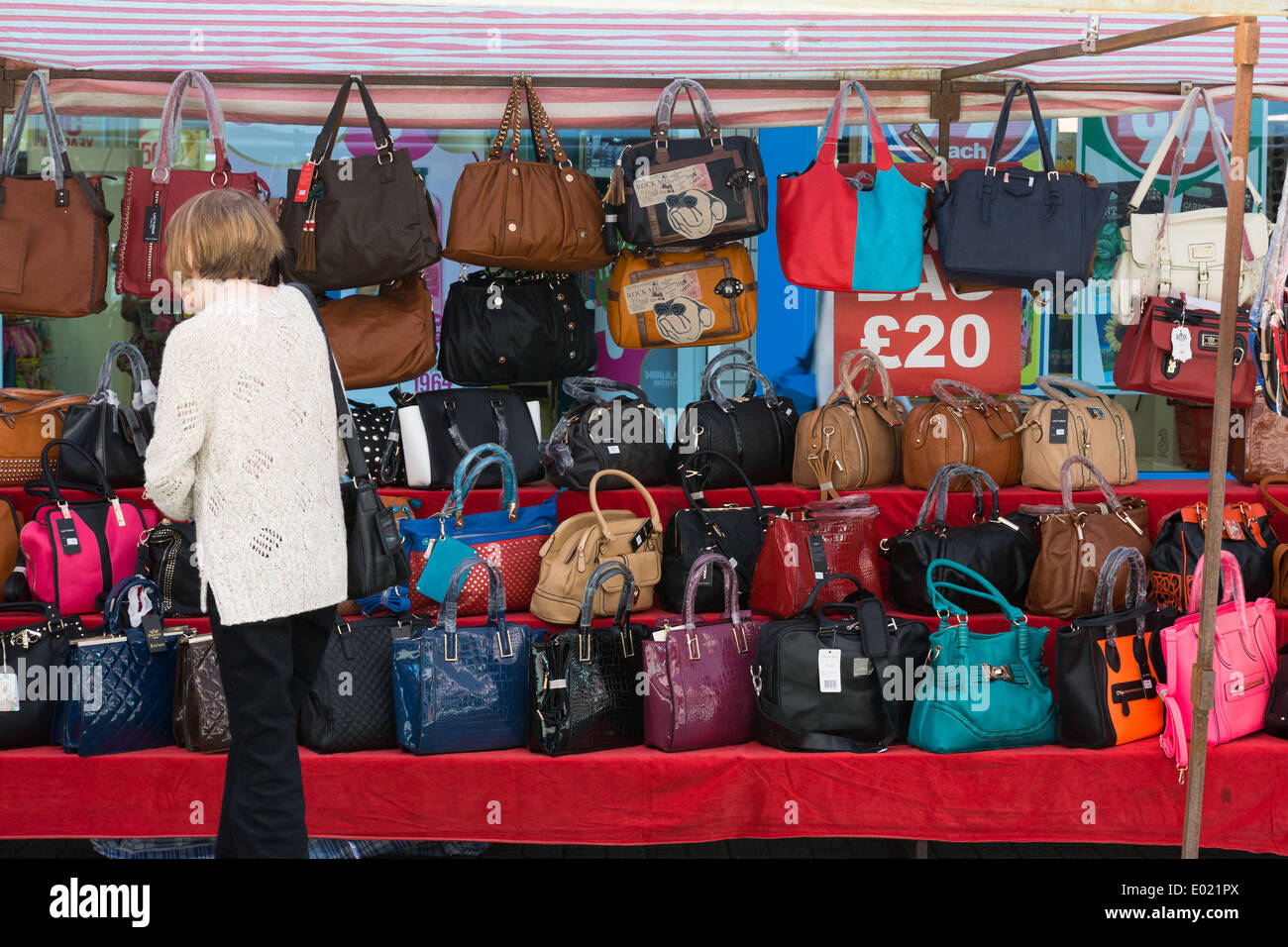 Una donna accede la merce su una mano-bag in stallo un mercato Foto Stock