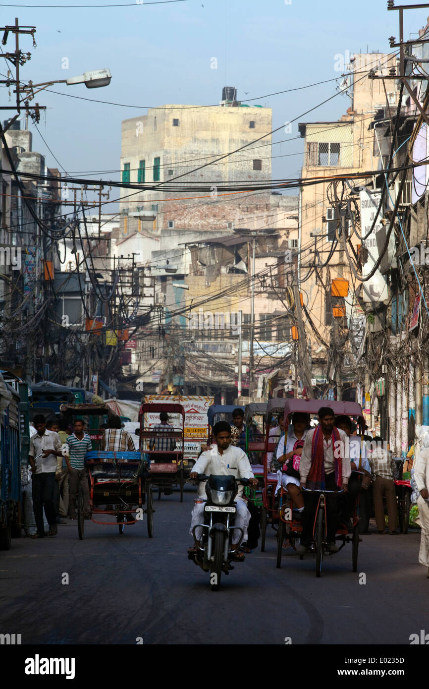 Un rickshaw wallah cicli attraverso una strada di Vecchia Delhi, India Foto Stock