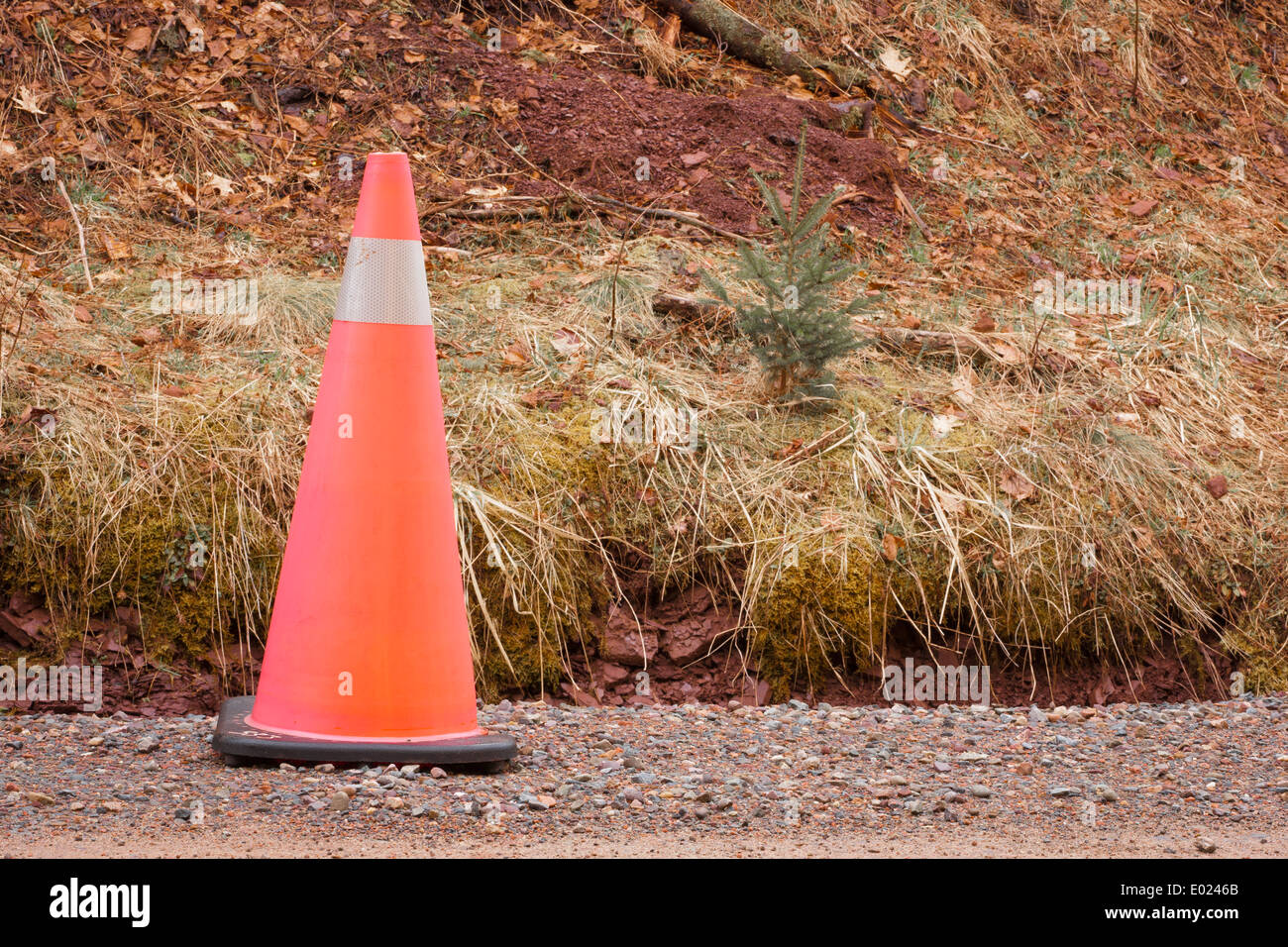 Cono di traffico su una strada sterrata a fianco di un piccolo fosso. Foto Stock