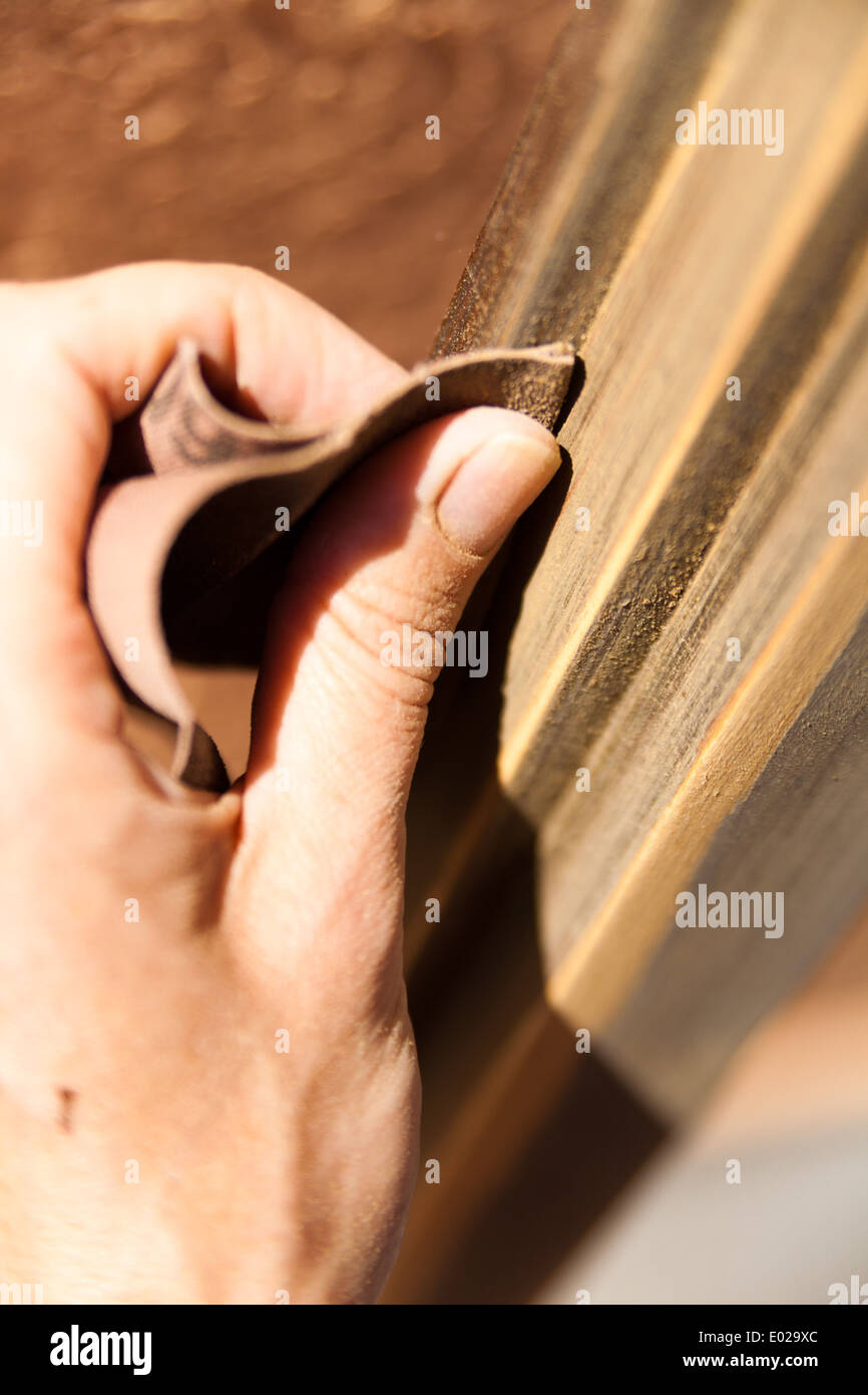 Le mani di una donna con la carta vetrata facendo lavori di DIY su infissi in legno Foto Stock