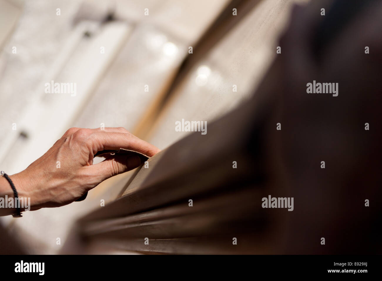 Le mani di una donna con la carta vetrata facendo lavori di DIY su infissi in legno Foto Stock