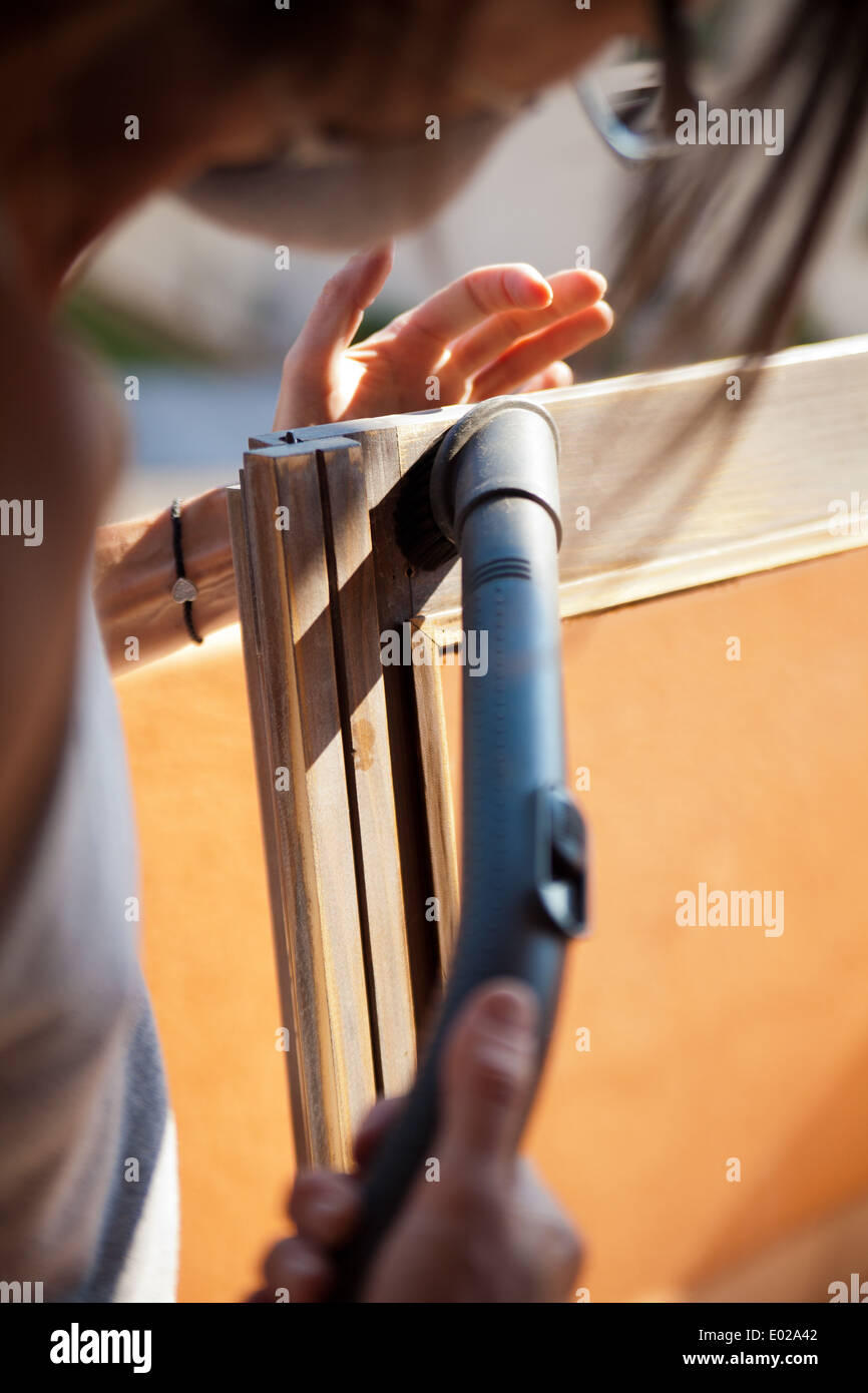 Do it yourself scena circa una donna la rimozione di segatura dalla sua finestra lucido sotto il sole Foto Stock