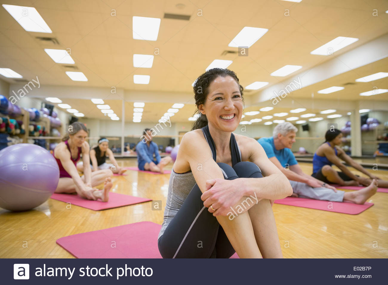 Donna sorridente sul materassino yoga nella classe di esercizio Foto Stock