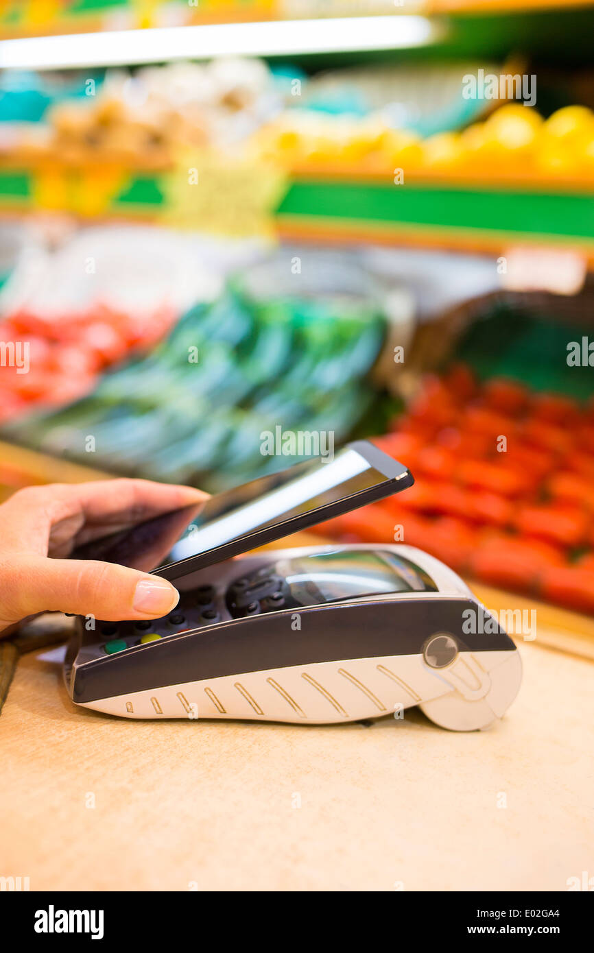Femmina pagamento elettronico close-up cell phone shop mano lettore elettronico Foto Stock