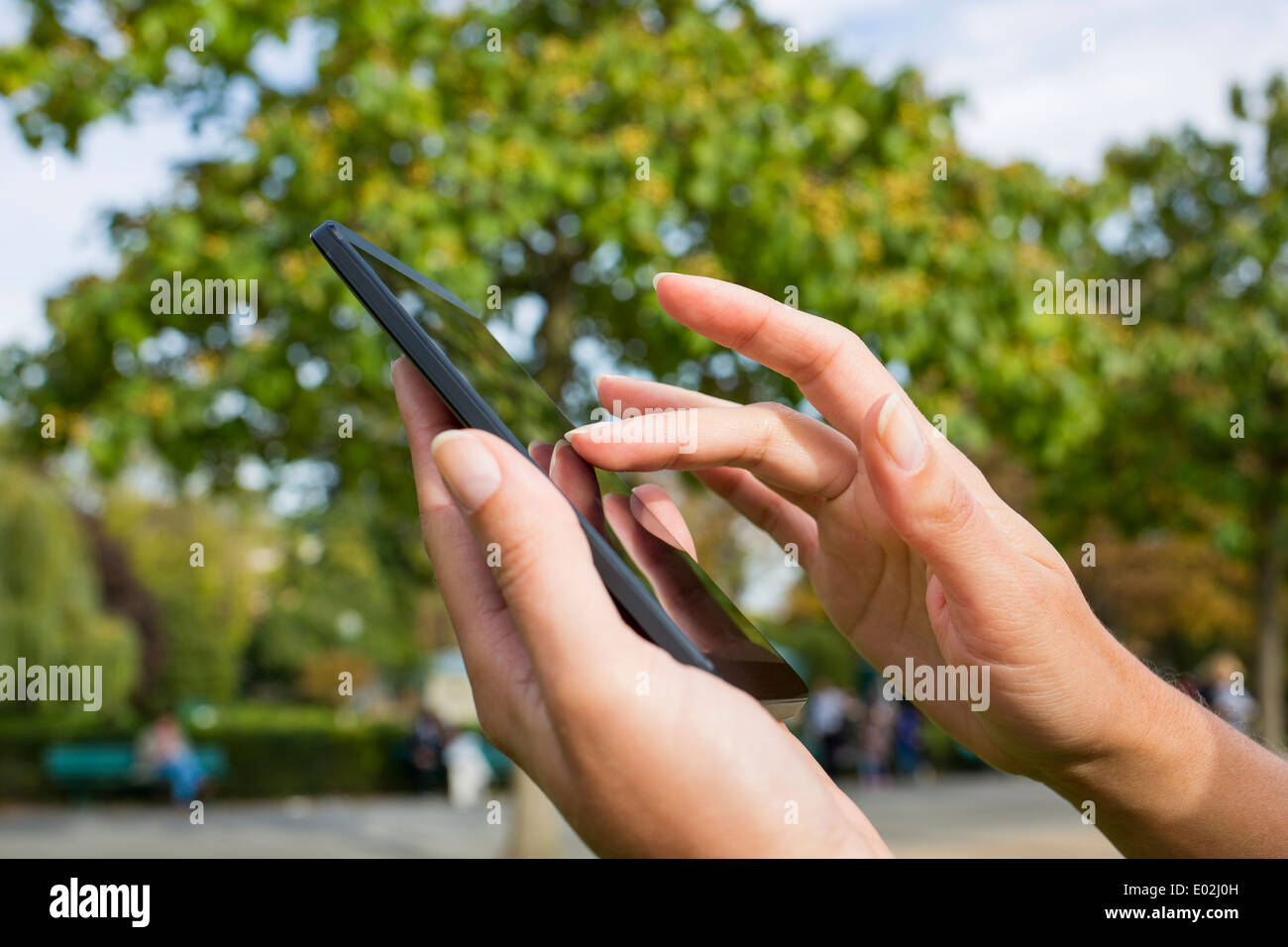 Close-up femmina telefono mobile alberi Panchetta outdoor messaggi sms e-mail Foto Stock