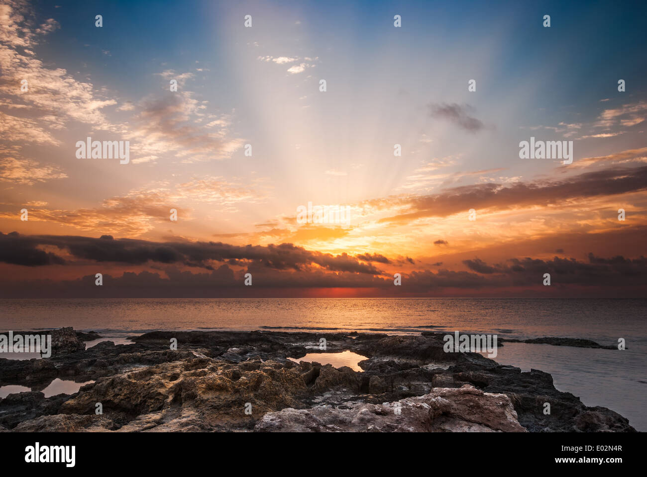 Spiaggia rocciosa e Sky con Sunray sulla Mattina nuvoloso Foto Stock