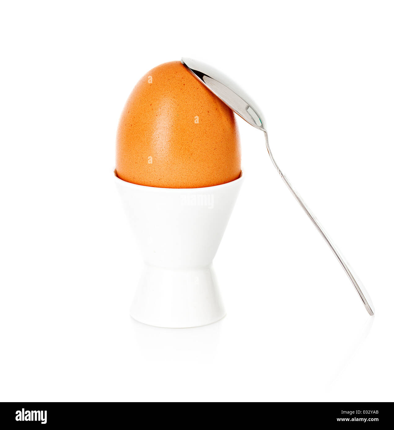 Bollito uovo marrone in coppa, su di un supporto con un cucchiaio isolato su bianco Foto Stock
