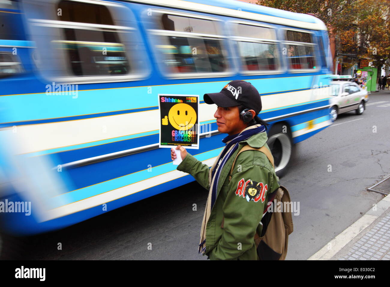 LA PAZ, Bolivia, 30 aprile 2014. Uno studente con un AC/DC 'autostrada all'inferno" badge sulla sua giacca detiene una targhetta durante n. Avvisatore acustico giorno / Dia de la No Bocina, una campagna per incoraggiare i driver per utilizzare il loro corno inferiore e a ridurre l' inquinamento acustico in città. La Paz è famosa per il suo traffico caotico; il Municipio corre frequentemente le campagne in materia di sicurezza stradale e a ridurre la congestione e simili. Credito: James Brunker / Alamy Live News Foto Stock