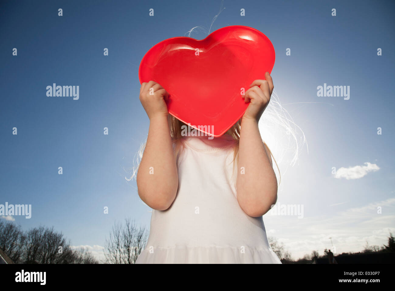 Un bambino tenendo un cuore rosso forma. Foto Stock