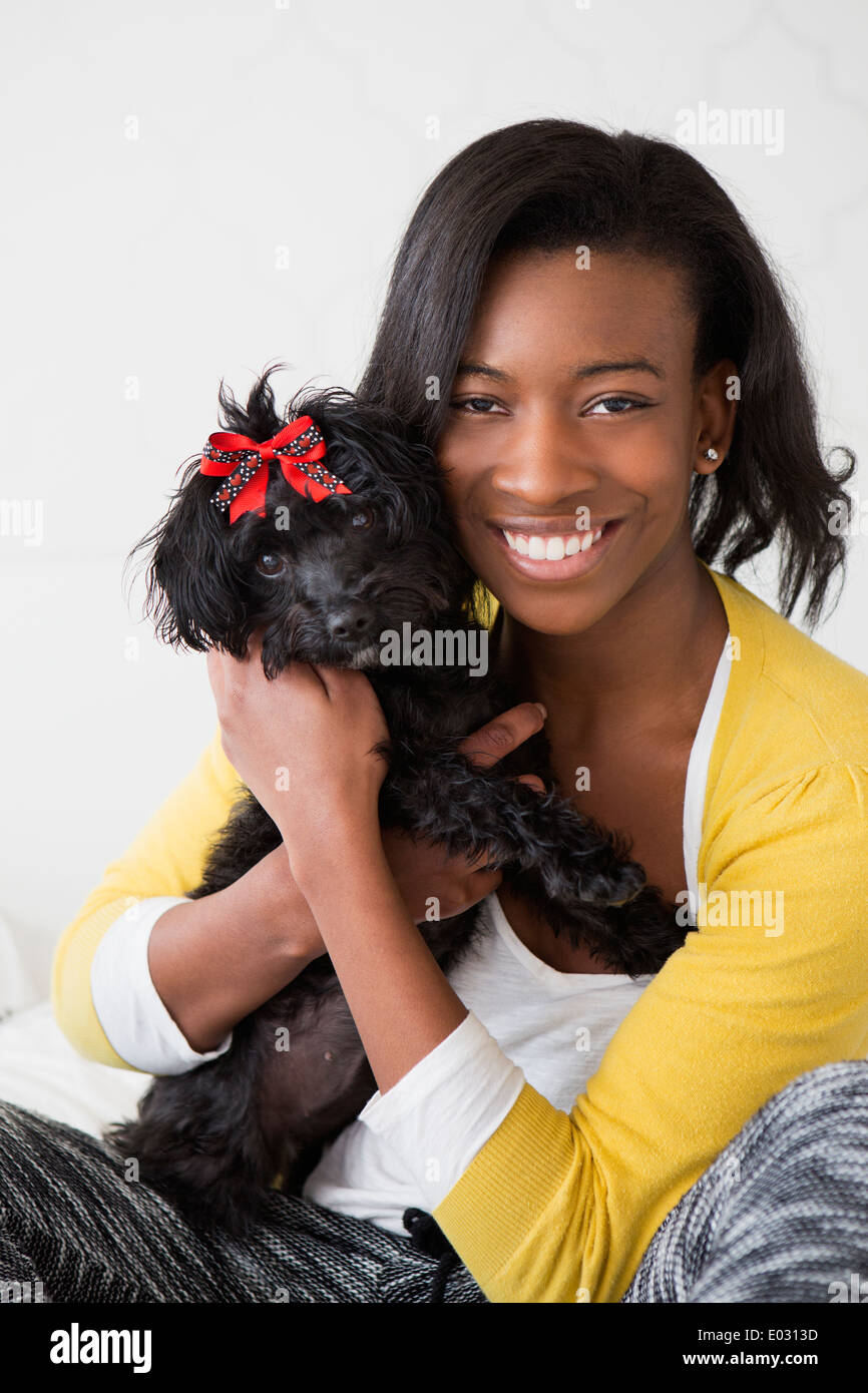 Una giovane ragazza sorridente mentre tiene il suo nero piccolo cane. Foto Stock