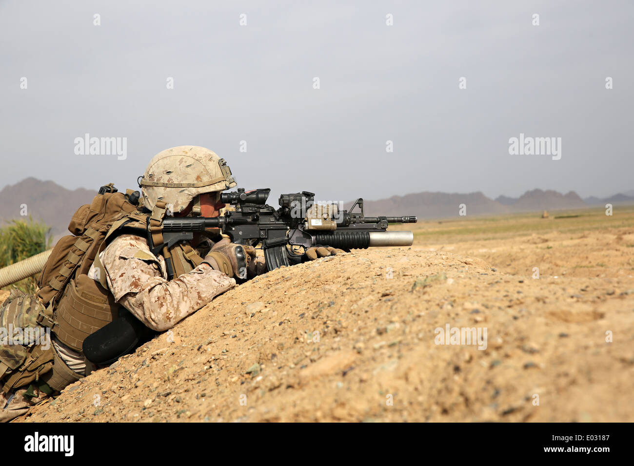 US marina il sergente Sloan Seiler detiene una posizione lungo un berm come la sua squadra attraversa un campo al di fuori di un villaggio durante un'operazione di compensazione missione 25 aprile 2014 nel villaggio di Larr, provincia di Helmand, Afghanistan. Foto Stock