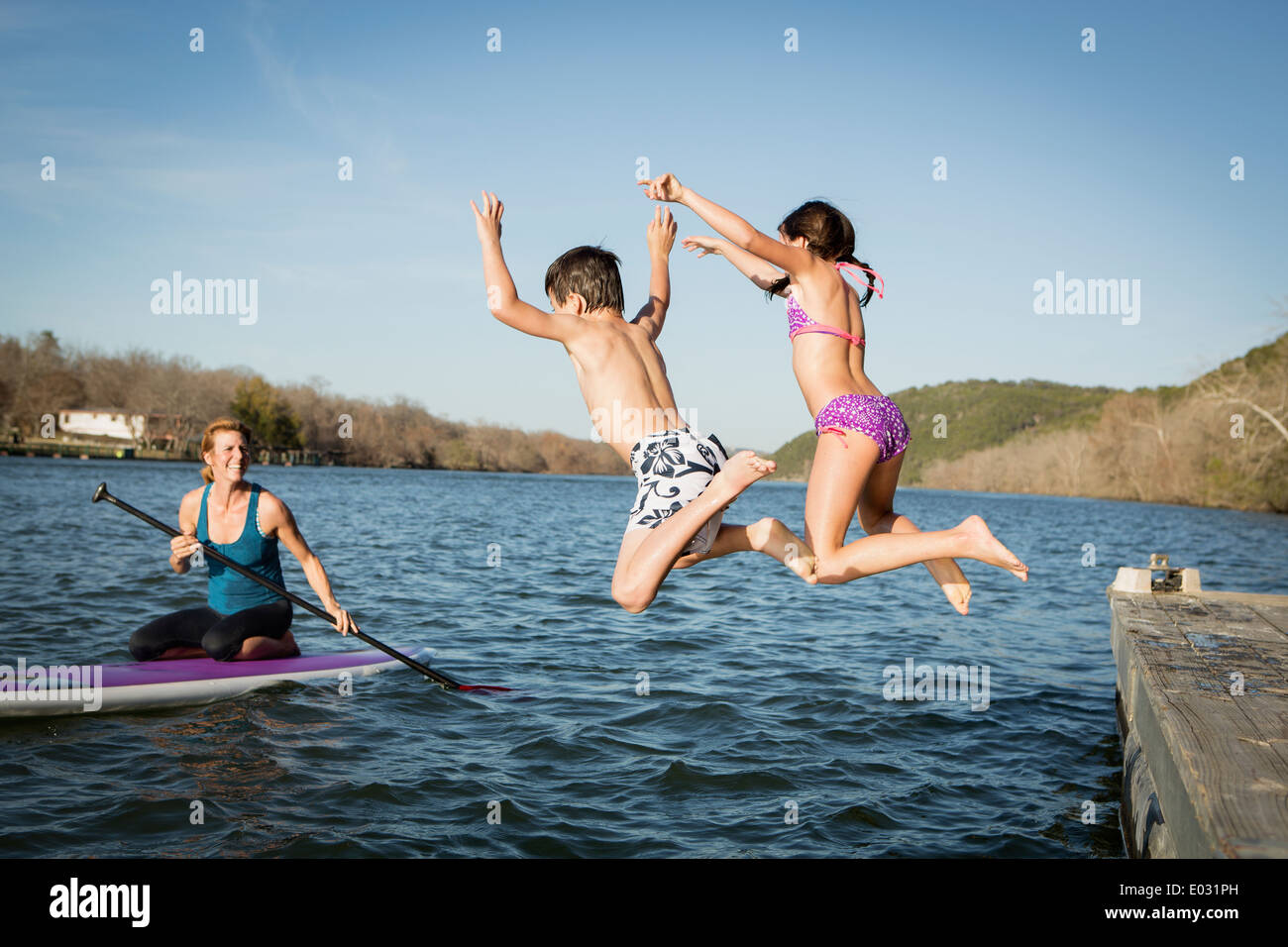 Due bambini saltando in acqua da un molo. Foto Stock